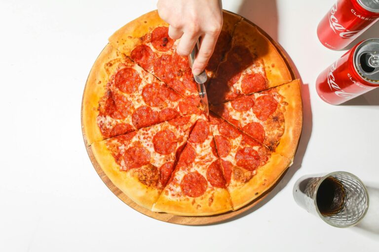 person slicing a pizza with a pizza cutter